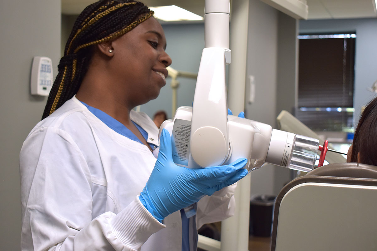 MedQuest College Comprehensive Dental Assisting student aligning dental x-ray machine
