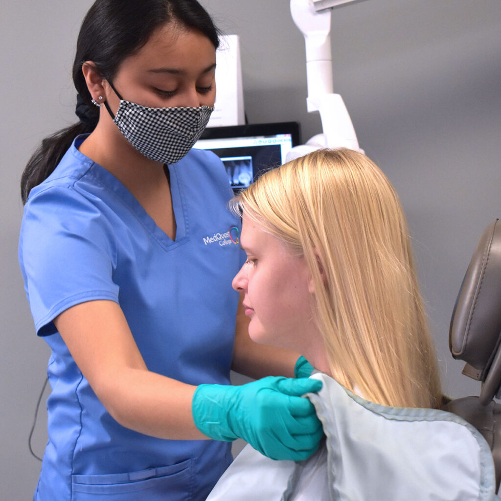MedQuest College Comprehensive Dental Assisting student placing x-ray shield on patient