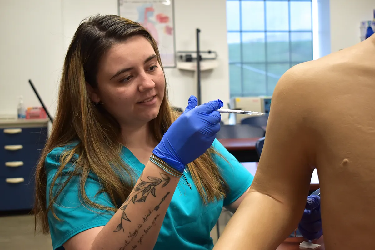 medical assistant student practicing how to administer an injection
