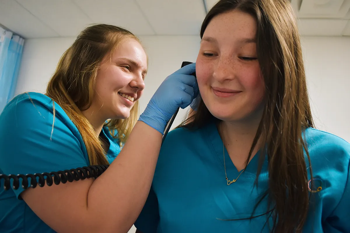medical assistant student checking ear of a patient