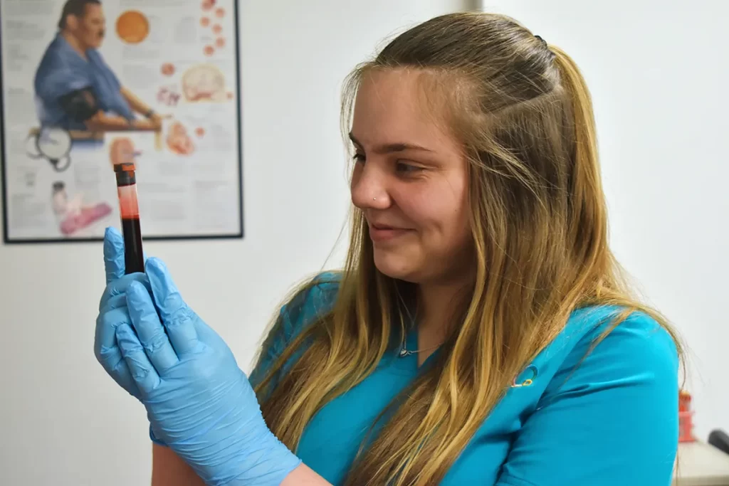 medical assistant student looking at vial of blood
