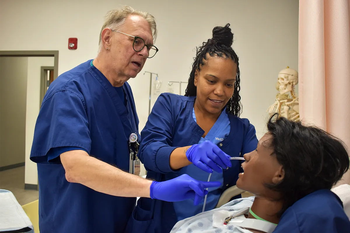 nursing teacher and student working together with a mannequin